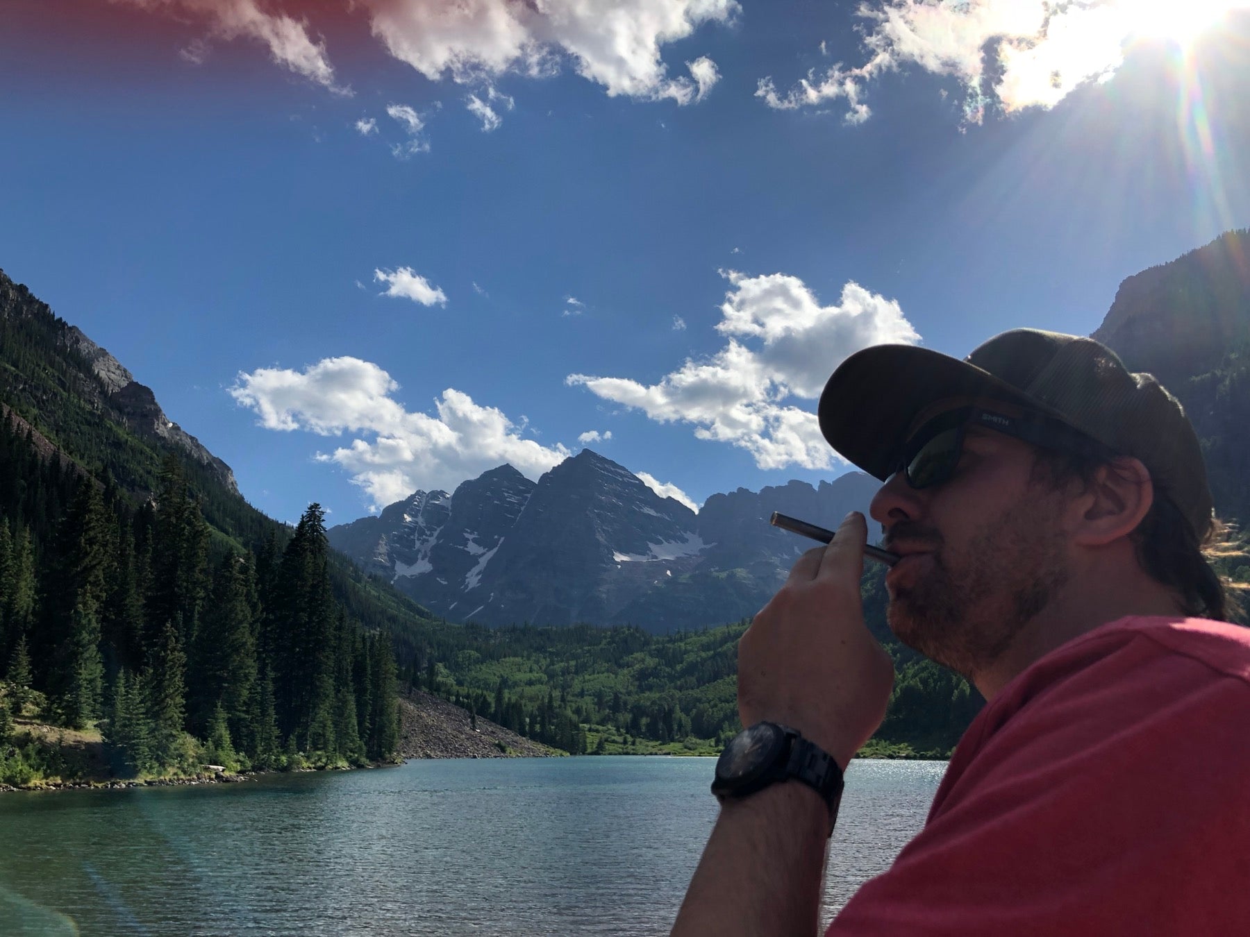 Man inhaling MONQ diffuser at a sun-drenched lake with mountains — connecting the olfactory system to the botanical baseline it evolved with