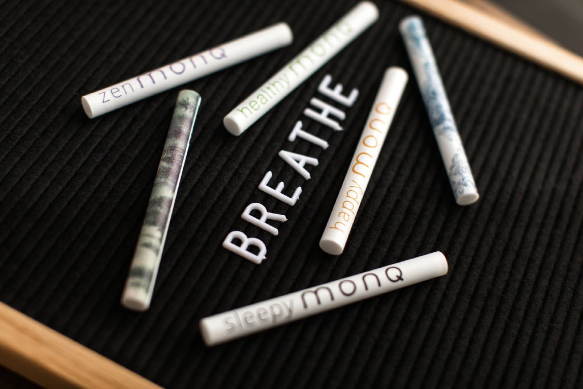 Six MONQ diffusers arranged around BREATHE letterboard — terpene-rich botanical blends for the olfactory system