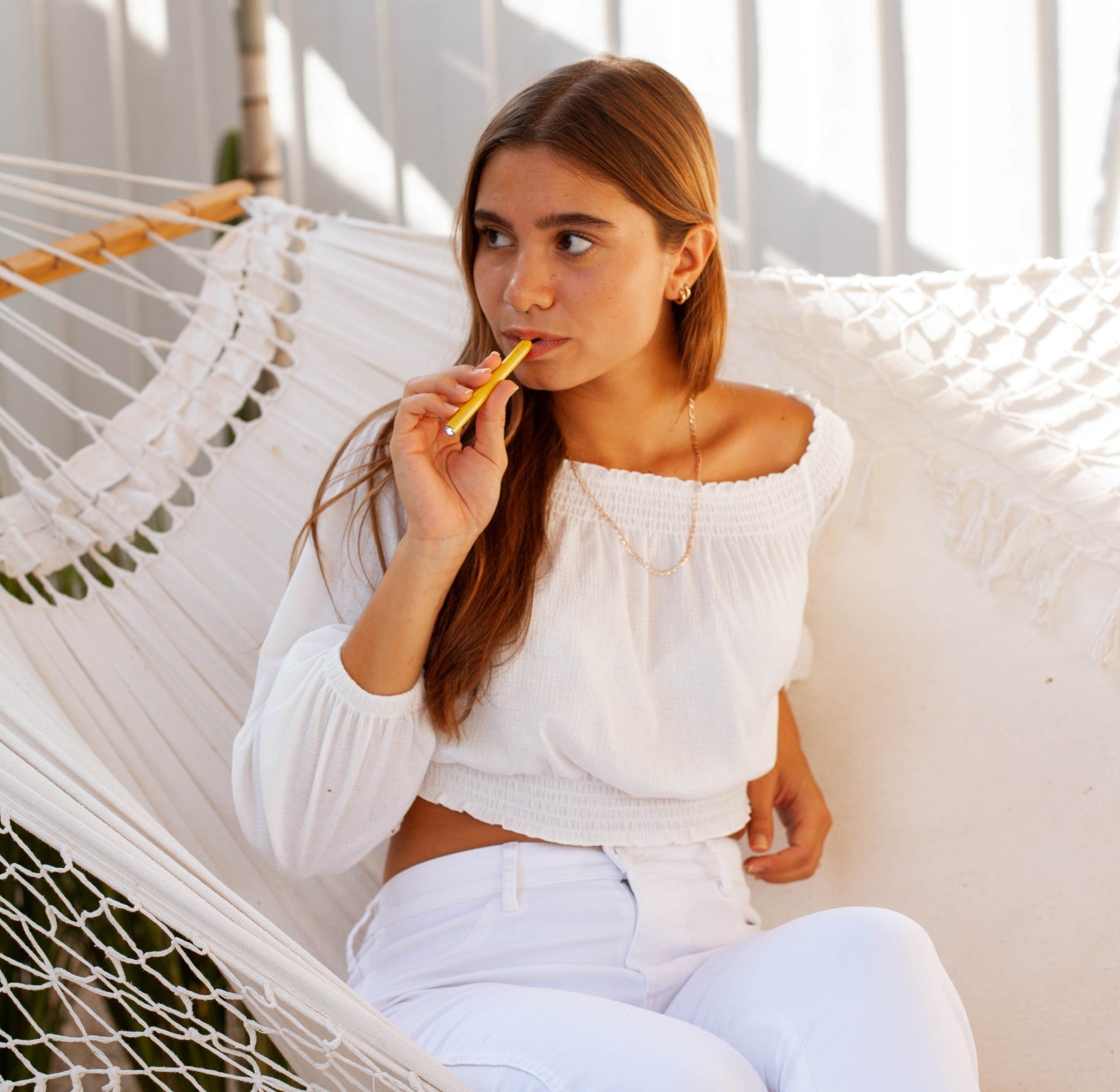 A woman sitting on a hammock breathes in from the Happy MONQ diffuser.