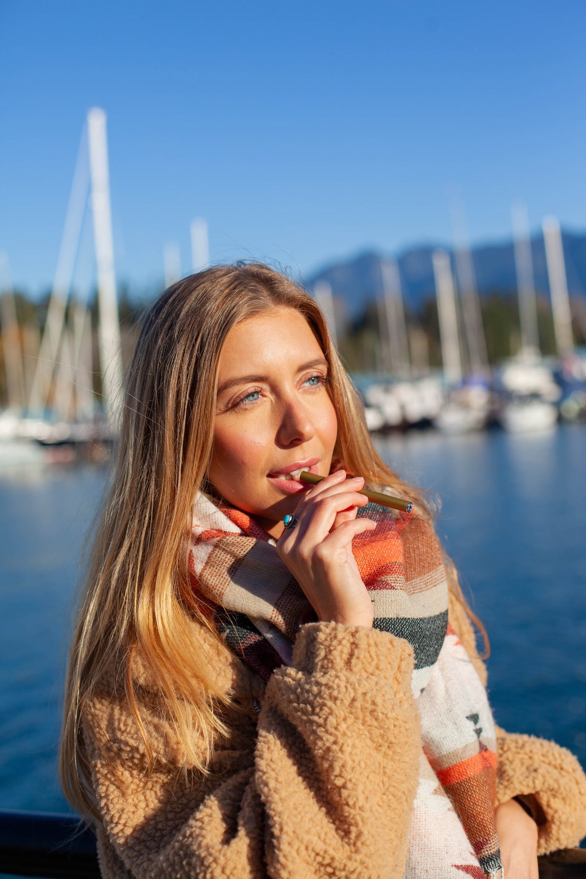 Woman holding a MONQ personal aromatherapy diffuser in warm light beside the water